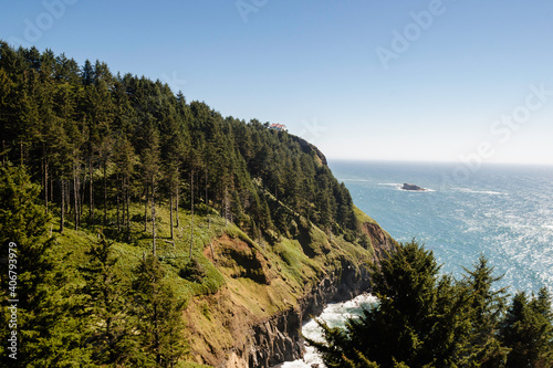 A lush green hill sits up over the ocean with cliffs plunging down towards the water below.