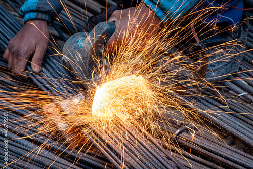 Closeup of a man cutting TMT Steel Bar with circular grinder used in construction. photo