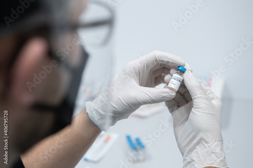 CU COVID-19 vaccine in male doctor hands, male doctor holds bottle with vaccine for coronavirus cure. Concept of corona virus treatment, injection, vaccination, clinical trial during pandemic