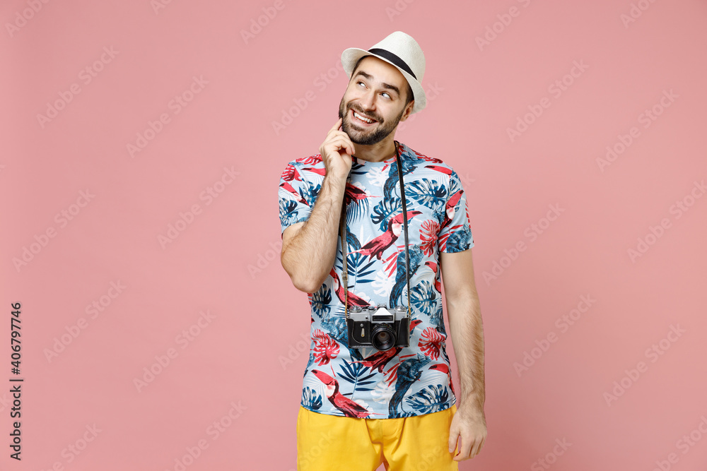 Pensive young traveler tourist man in summer basic clothes hat with photo camera put hand prop up on chin isolated on pink background. Passenger traveling on weekends. Air flight journey concept. Pensive young traveler tourist man in summer basic clothes hat with photo camera put hand prop up on chin isolated on pink background. Passenger traveling on weekends. Air flight journey concept.