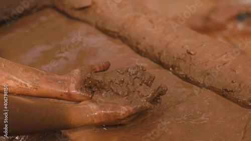 A woman smears her skin with therapeutic cosmetic mud and clay from a natural lake. Cleaning face and body skin with spa cleansing mud. Skincare beauty treatment.