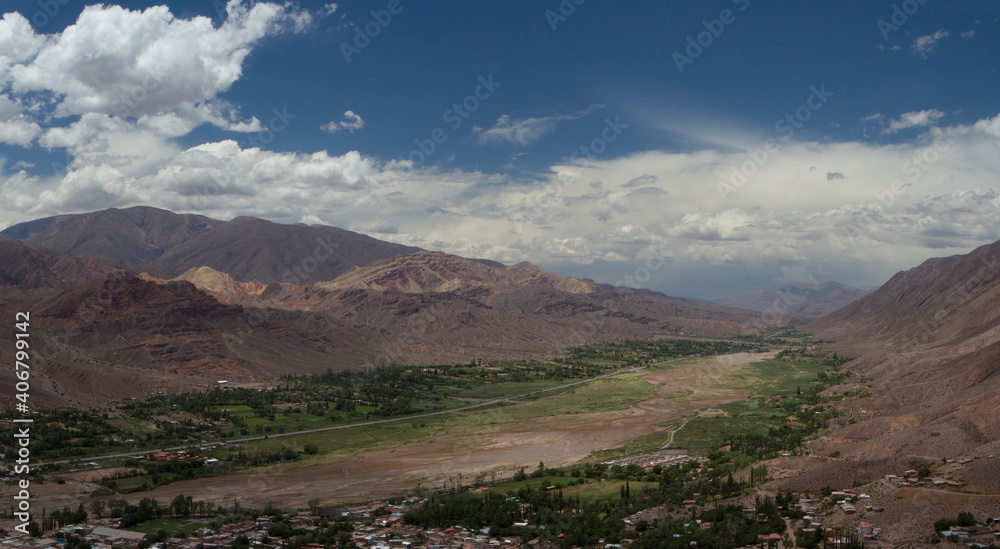 Idyllic landscape with beautiful sky. Panorama view of Humahuaca ravine, brown mountains, Andes desert, green valley and Tilcara village in Jujuy, Argentina. 