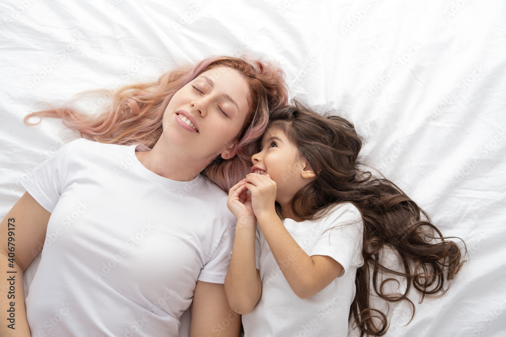 young mother and little active daughter lying in bed at home, having fun. young mother and little active daughter lying in bed at home, having fun.