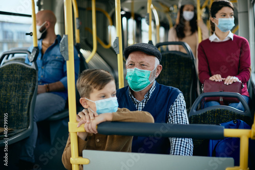 Senior man and his grandson commuting by public transport during coronavirus pandemic.
