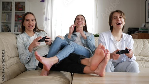 Teenager girls at home triplet sisters have fun play console games sitting on couch at home stay isolated under quarantine