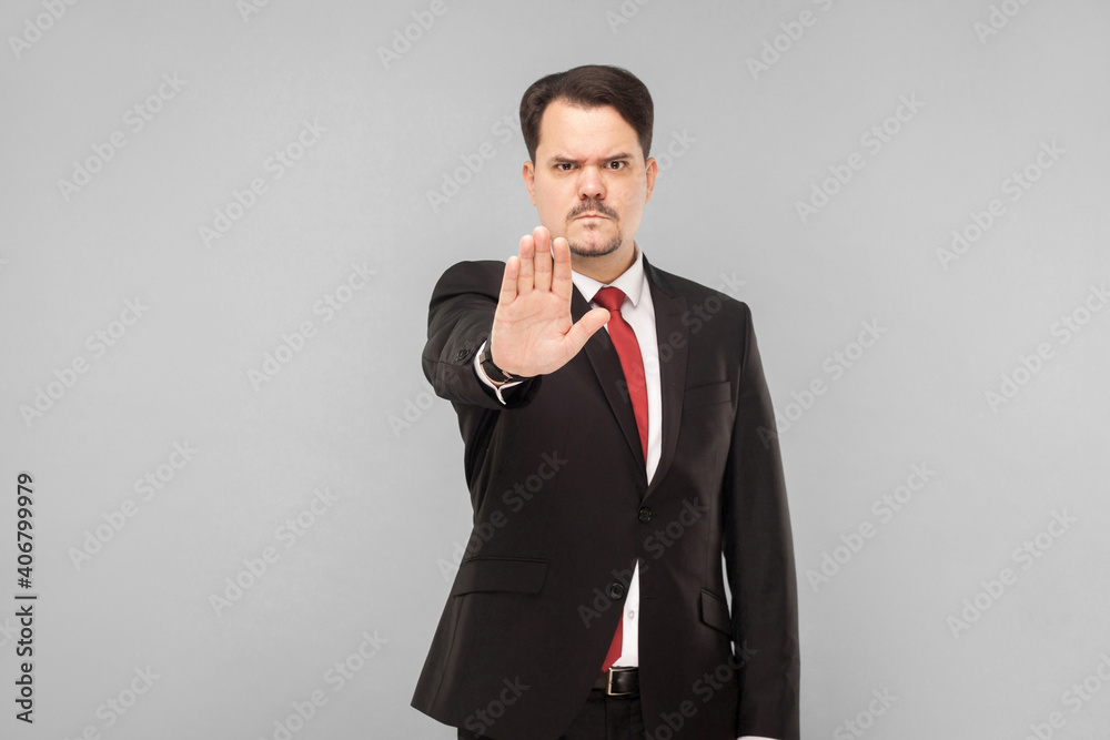 angry business man showing hand. Stop this, do not want to listen anymore, go out. indoor studio shot. isolated on gray background. businessman with black suit, red tie and mustache looking at camera angry business man showing hand. Stop this, do not want to listen anymore, go out. indoor studio shot. isolated on gray background. businessman with black suit, red tie and mustache looking at camera
