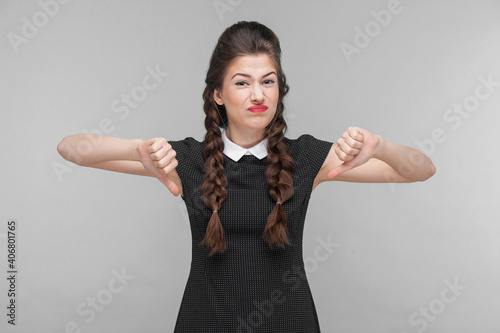 Disagree young woman demonstrate dislike sign. Indoor, studio shot isolated on gray background photo