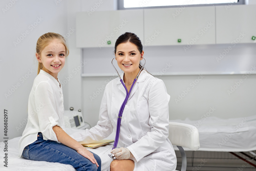 portrait of cheerful kid girl patient and female doctor posing at camera, sit smiling. child visit pediatrician. in hispital. medicine and healthcare concept portrait of cheerful kid girl patient and female doctor posing at camera, sit smiling. child visit pediatrician. in hispital. medicine and healthcare concept