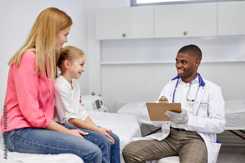 Obraz premium black male doctor listen consult girl make notes in patient card at medical checkup appointment, pretty child with mother visit pediatrician talk in clinic, children healthcare concept