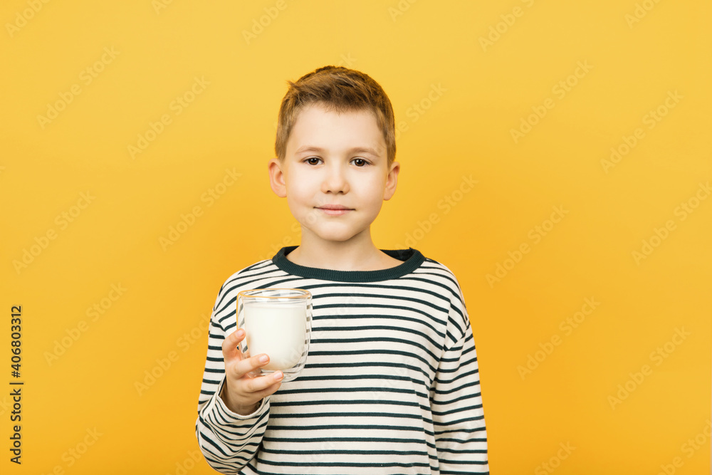 Young Caucasian boy holding a glass of milk isolated on yellow background Young Caucasian boy holding a glass of milk isolated on yellow background
