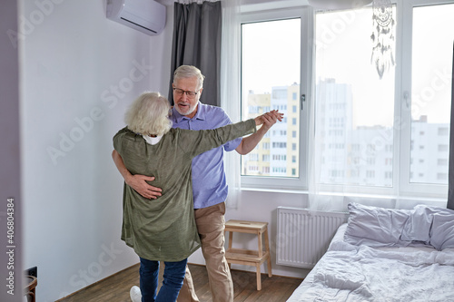 senior couple have fun dancing at home, romantic mature grey-haired man and woman feel energetic active enjoy family retirement weekend, spend holidays together