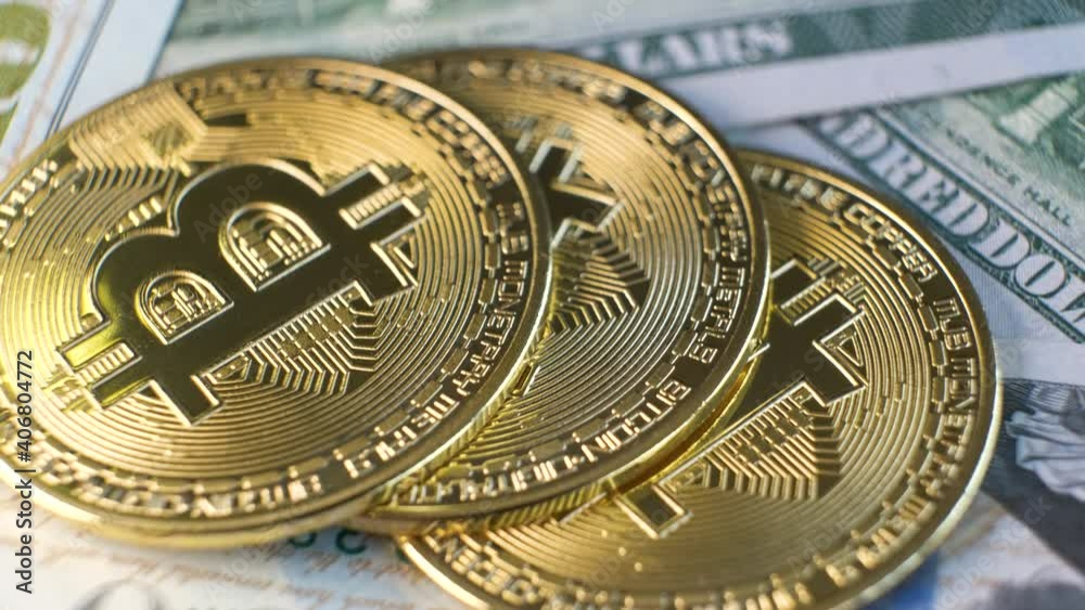 Close up of metal shiny bitcoin crypto currency coins on US dollar bills. Electronic decentralized money concept.