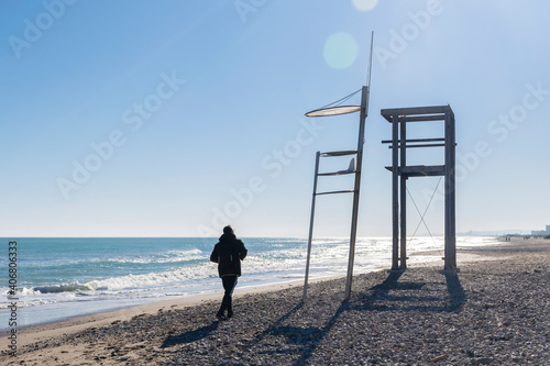 Man walking at the beach. Lifeguard tower