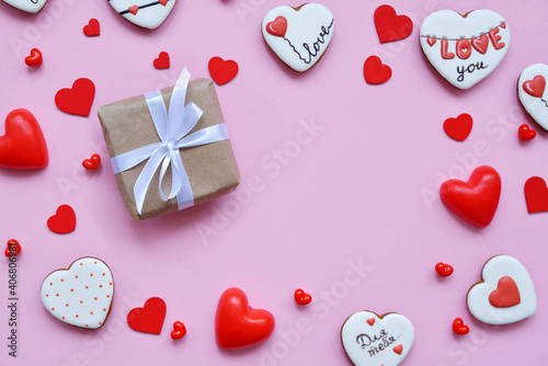 red hearts of different shapes on a solid background. gift wrapped in craft paper wrapped with white gift ribbon. space for text