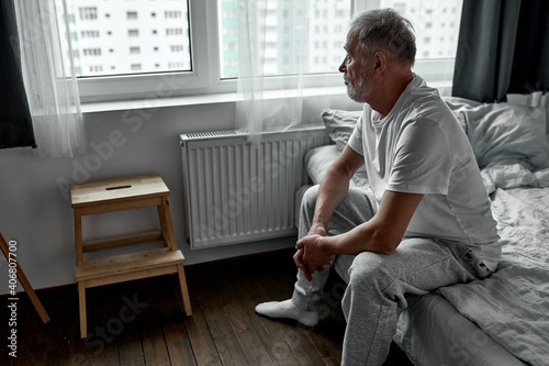 elderly man sitting alone at home, social distancing and self isolation in quarantine lockdown for Coronavirus