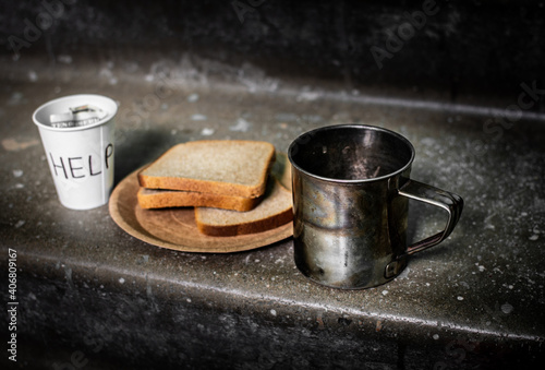 A paper plate of bread stands on a concrete staircase stands, in the background a homeless man