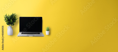 Flat lay top view office desk working space with laptop on yellow background. Copy space.