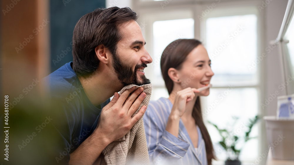 Young couple brushing teeth in front of mirror indoors at home. Young couple brushing teeth in front of mirror indoors at home.