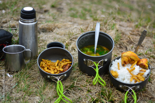 Dining menu when climbing a mountain. Food in a portable dining area with side dishes of rice, chicken, tempeh and vegetables. Moung gede pangrango national park, indonesia
