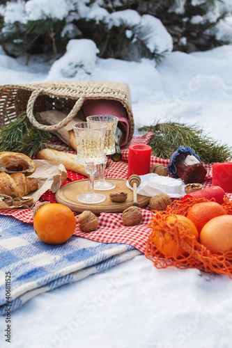 Fototapeta Naklejka Na Ścianę i Meble -  Romantic picnic setting in winter park, color blanket. Fresh food, cheese, oranges, croissants, wine and walnuts. Outdoor relaxing, fresh air eating.