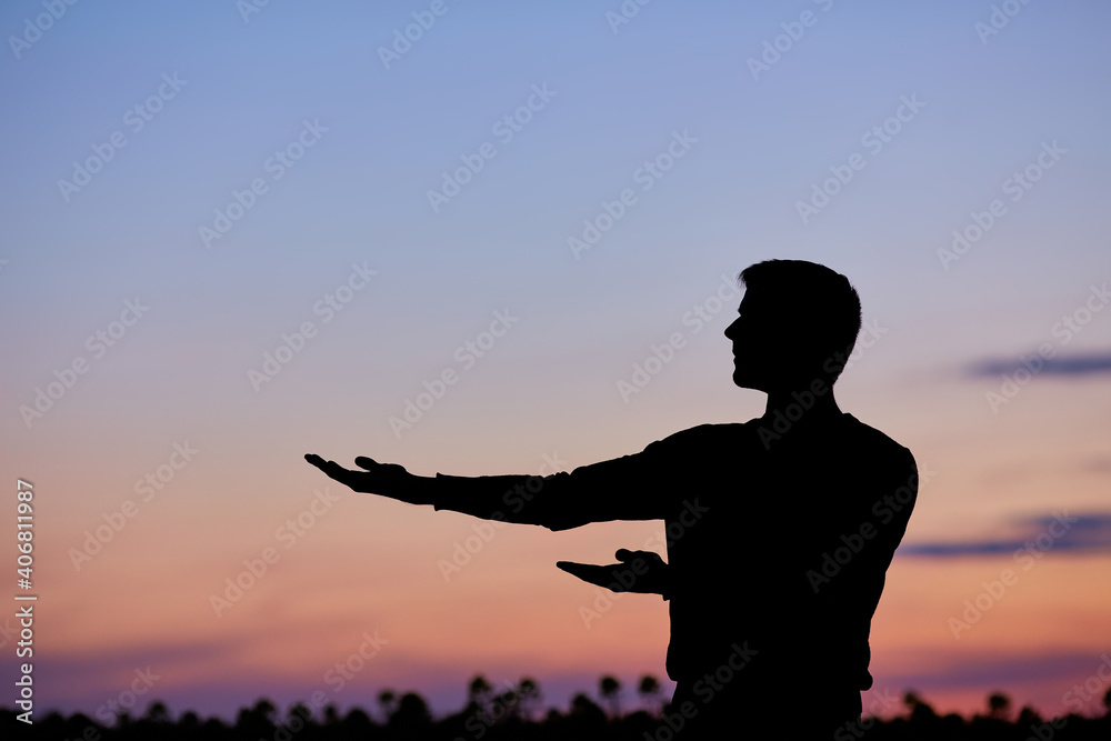 Fototapeta premium Men silhouette at sunset, human body over natural colorful sky background, hands up having fun