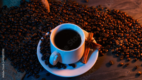 white cup of espresso coffee  roasted coffee beans. Dark background with neon popular trend lighting