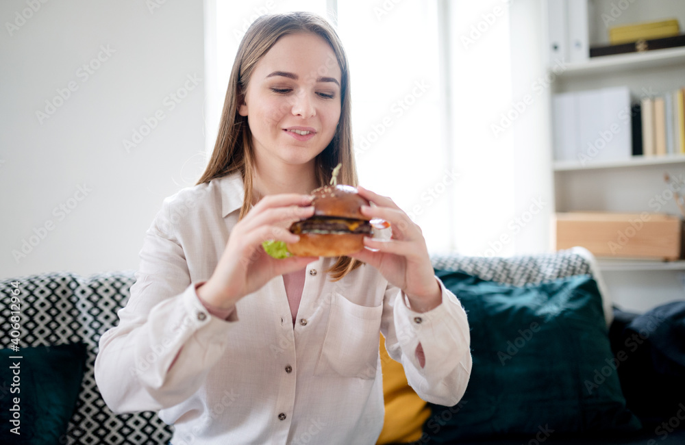 Young woman with take away hamburger at home, coronavirus and food delivery concept. Young woman with take away hamburger at home, coronavirus and food delivery concept.