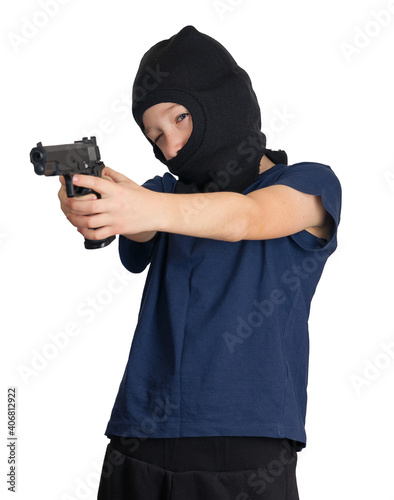 boy in a mask or balaclava with a pistol in his hands, takes aim at someone, on an isolated background. child crime symbol