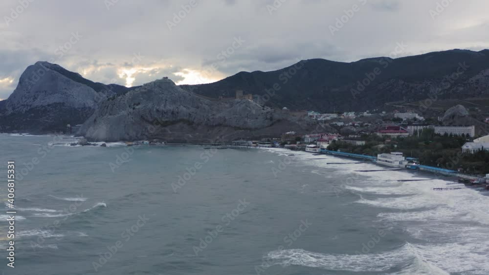 Mountain and sea bay landscape from drone in resort city. Mountain range over Sudak, sea waves splashing on beach. Aerial view highlands on urban background. Mountain and sea bay landscape from drone in resort city. Mountain range over Sudak, sea waves splashing on beach. Aerial view highlands on urban background.