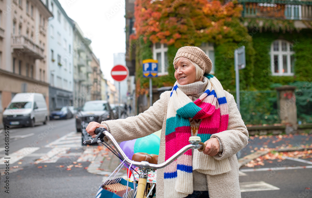 Obraz premium Senior woman with bicycle crossing road outdoors in city.