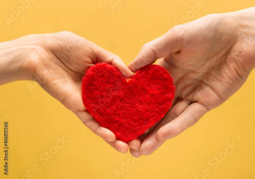 Heart symbol of lovers in the hands of a man and a woman on a yellow background. Valentine s Day concept.