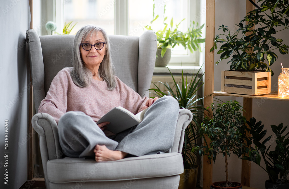 Portrait of senior woman sitting indoors on sofa at home, reading book. Portrait of senior woman sitting indoors on sofa at home, reading book.