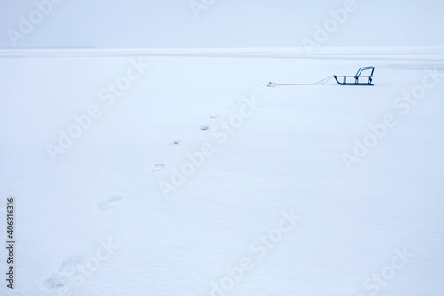 Gorgeous winter landscape with feet path and lonely sledge on icy frozen lake like a desert, background with copy space, winter romantic, silence and wild nature