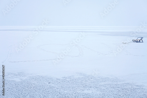 Heart shape feet path in the snow on the frozen lake. Winter romantic, silence and wild nature, icy landscape, concept for winter lovers and valentine day
