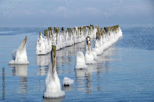 wooden piles of the old pier covered with ice in frosty winter weather © dafna_nb