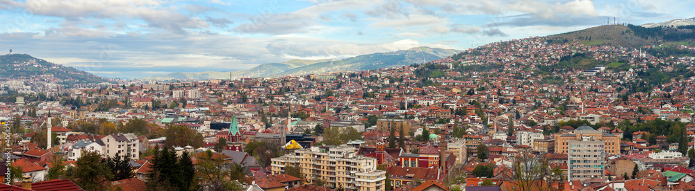 Panoramic view over Sarajevo and the surrounding hills under a blue sky with clouds; Bosnia and Herzegovina.