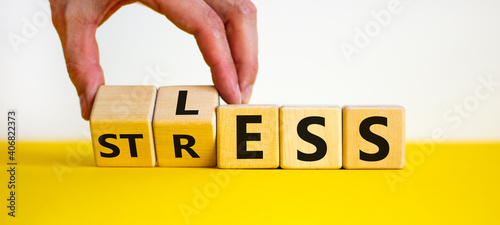 Having less stress or being stress-less. The word 'STRESS' and 'LESS' on wooden cubes. Male hand. Beautiful yellow table, white background, copy space. Business and psychological less stress concept. photo