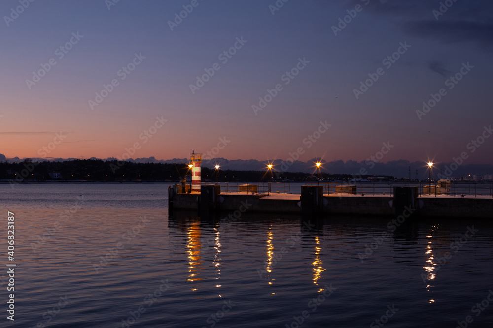 Klaipeda city, Lithuania in January. A lonely small lighthouse in front of dark sunset sky