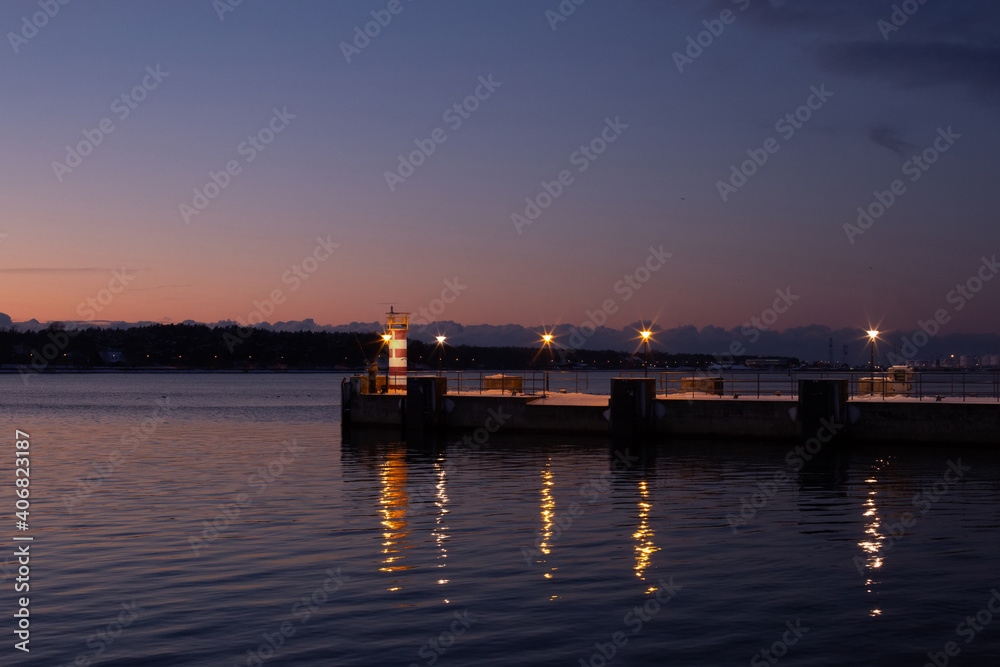 Klaipeda city, Lithuania in January. A lonely small lighthouse in front of dark sunset sky Klaipeda city, Lithuania in January. A lonely small lighthouse in front of dark sunset sky
