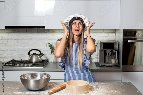 Young woman shocked in the kitchen, meal of flour.