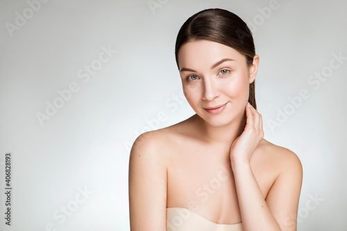 Close up of a beautiful brunette caucasian woman with fresh clean natural skin and soft smile on her face. Neutral, daily make up.