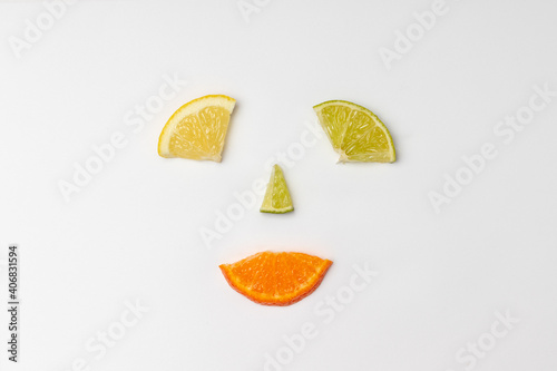 Citrus fruit slices minimal flat lay on white background arranged to make happy smiling face. Creativity, happiness and idea concept. photo