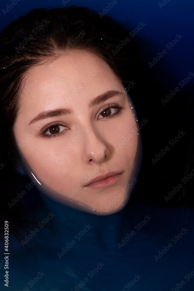 portrait of attractive brunette woman topless in blue liquid. in bathtub with colored water. drowning girl