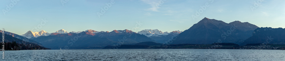 Panoramic landscape at lake surrounded by mountains. Beautiful sunset light on Eiger, Monch and Jungfrau at lake thun.