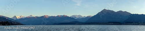 Panoramic landscape at lake surrounded by mountains. Beautiful sunset light on Eiger, Monch and Jungfrau at lake thun. © Adrian
