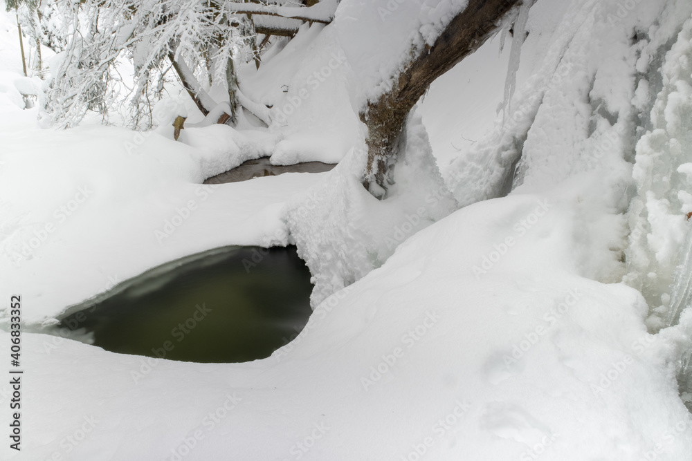 Vereister Wasserfall eingebettet in eine Schnee und Waldlandschaft Vereister Wasserfall eingebettet in eine Schnee und Waldlandschaft