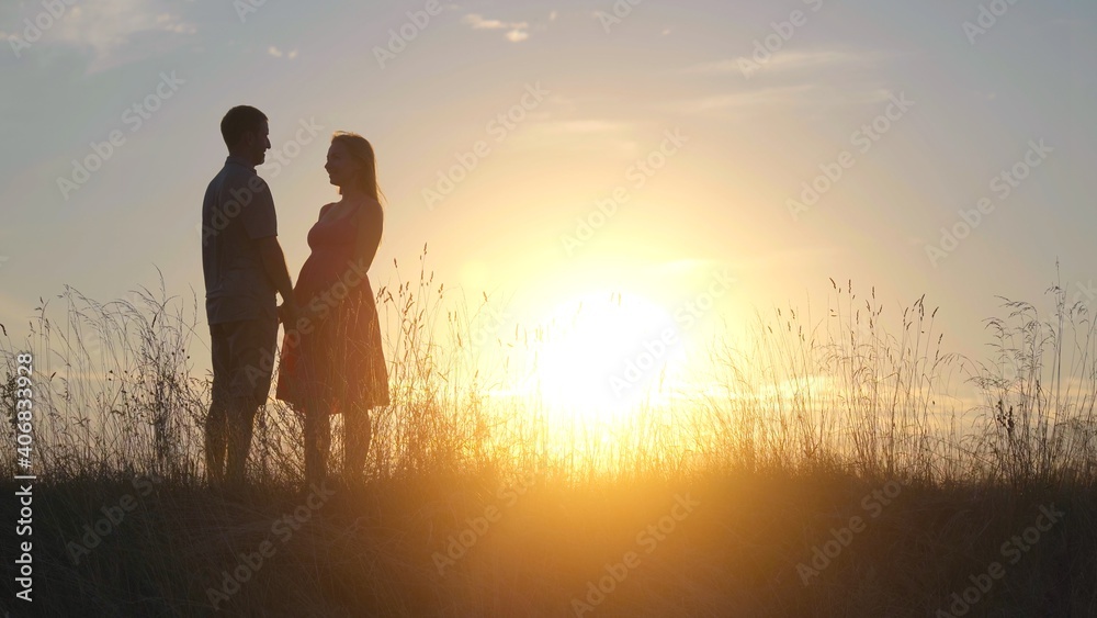 Silhouettes of happy young parents against the background of the evening sun.