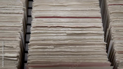 Old filing cabinet opening. Man's hand and files seen from above.