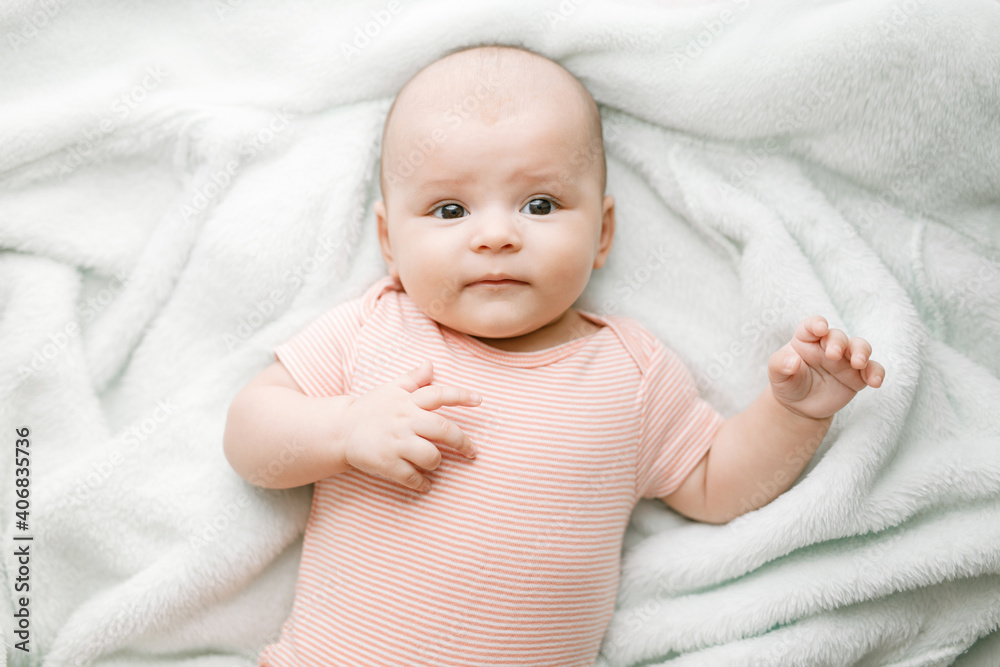 Adorable baby in sunny bedroom. Newborn baby is resting in bed with a warm soft blanket. Family morning at home. Smiling child looking at camera. Adorable baby in sunny bedroom. Newborn baby is resting in bed with a warm soft blanket. Family morning at home. Smiling child looking at camera.