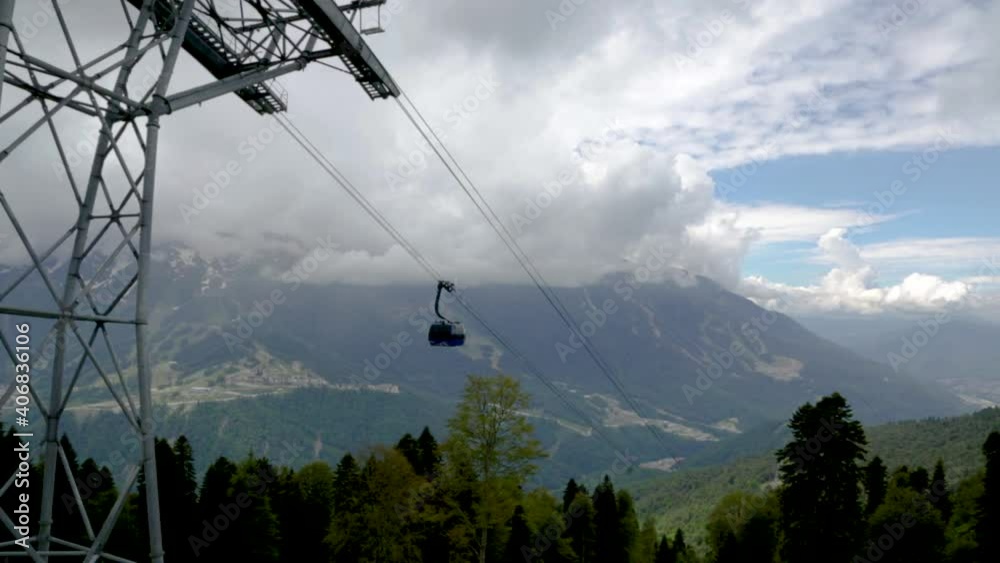 RUSSIA, ROSA KHUTOR - JUNE 11, 2016: Mountain resort Krasnaya Polyana, the cable car, cottages and hotels, high mountains, snowy peaks and clouds